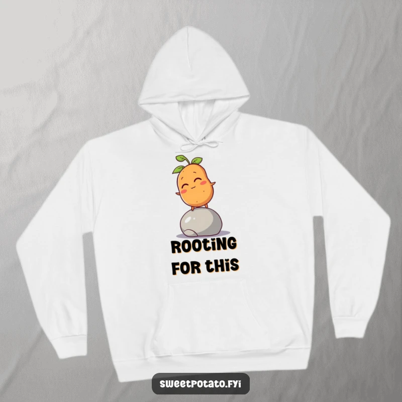 Funny sweet potato character winking, trying to balance on a rolling pebble, featured on a warm, hooded sweatshirt.